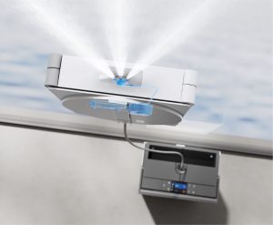 Ceiling-mounted fire sprinkler releasing a wide spray of water in a clinical or office room with equipment nearby